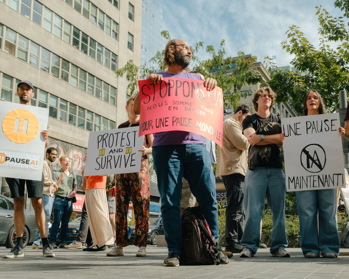 Des manifestants portent des pancartes appelant à une pause mondiale de l’IA
